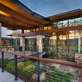 A modern house with large windows showcasing a contemporary design and a scenic sunset view from the outdoor patio.