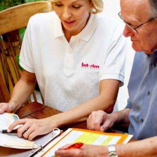 An advisor and an elderly man discussing paperwork outdoors.