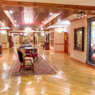 A luxurious hallway with wooden floors, elegant furniture, and decorative artwork and lighting.