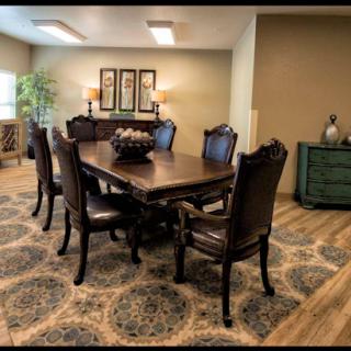 A spacious dining room featuring a wooden table with elegant chairs, complemented by decorative items and an area rug.