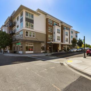 A modern apartment building located on a street corner in an urban residential area.