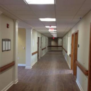 An empty hospital hallway with wooden flooring and ceiling lights.