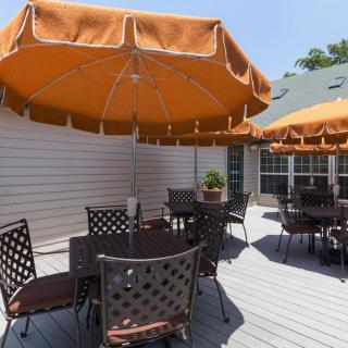 Outdoor patio with seating and orange umbrellas on a sunny day.
