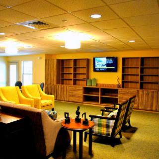 A cozy living room with comfortable seating, bookshelves, and a mounted television.