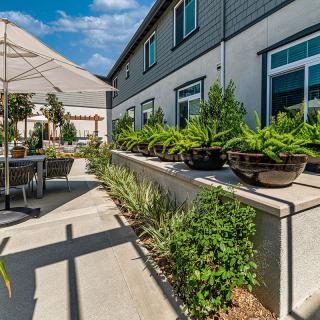A modern patio with potted plants and outdoor furniture beside a building.