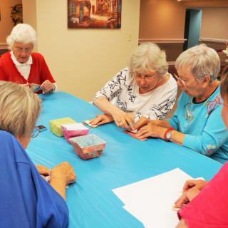 A group of seniors engaged in a crafting activity around a table.
