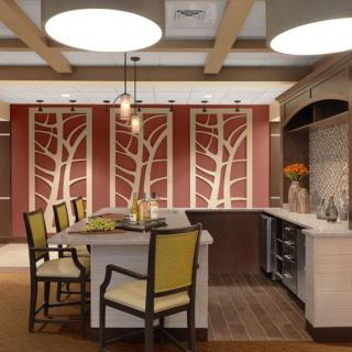 A modern kitchen interior featuring a central island with chairs, decorative art panels, and pendant lighting.