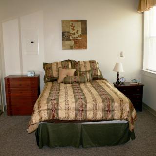A cozy bedroom with a neatly made bed, nightstand, and artwork on the wall.
