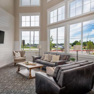 A spacious and modern living room filled with natural light, featuring large windows, comfortable sofas, a coffee table, and elegant decor.