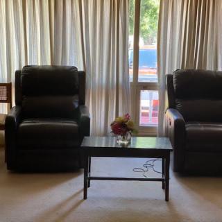 A cozy living room with two chairs and a small table in front of a window with curtains.