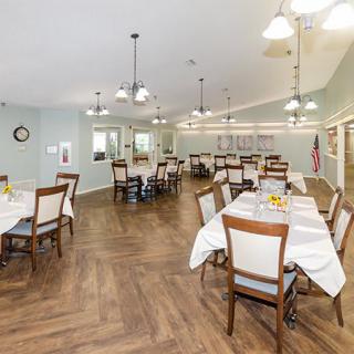 A spacious and well-lit dining room with neatly arranged tables and chairs.
