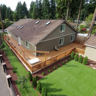 Aerial view of a suburban duplex with a large wooden deck and neatly maintained lawn.