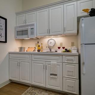 A modern kitchen with white cabinetry, a microwave, and a refrigerator.