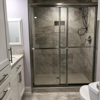 A modern bathroom with a tiled shower enclosed by glass doors and a vanity with drawers.
