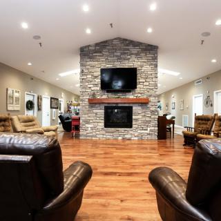 A cozy living room featuring a stone fireplace, hardwood floors, and comfortable leather seating.
