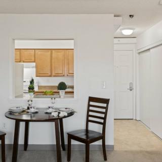 A minimalist dining area with a round table and two chairs, adjacent to a kitchen.