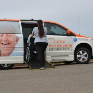 A caregiver helps a person in a wheelchair enter an accessible van designed for senior and mobility assistance.