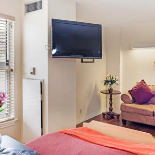 A cozy bedroom interior featuring a mounted television, comfortable sofa, and stylish decor.