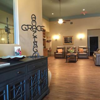 A cozy living room with comfortable seating, cross wall decor, and warm lighting.