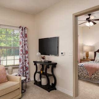 A cozy living room with a view into a bedroom, featuring elegant decor and neutral tones.