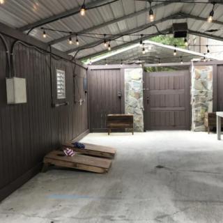 A well-lit garage interior with cornhole boards on a concrete floor.