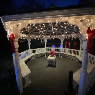 A beautifully decorated gazebo illuminated with string lights at night, creating a festive atmosphere.