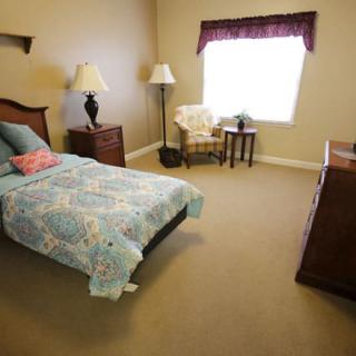 A cozy bedroom with a single bed, chair, and ample natural light from the window.