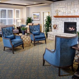A cozy living room featuring blue chairs and a fireplace.