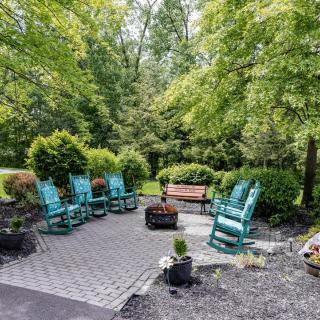 A peaceful patio area with turquoise chairs and a wooden bench surrounded by lush greenery.