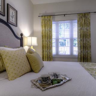 A cozy bedroom with a well-made bed, adorned with decorative pillows and illuminated by a bedside lamp.