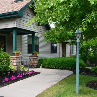 A charming house with a well-maintained garden, featuring a porch and a sidewalk lined with flowers.