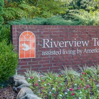 Sign for Riverview Terrace assisted living, surrounded by a garden.