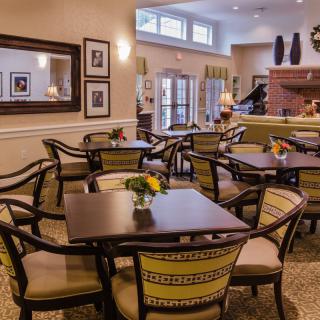 A cozy dining area with elegantly arranged tables and chairs, featuring warm lighting and tasteful decor.