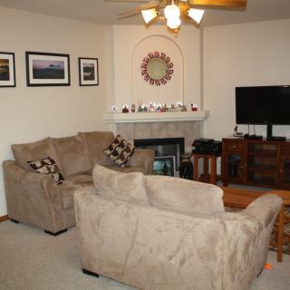 A cozy living room with sofas, a fireplace, and a TV.