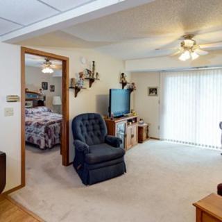 A cozy living room with an armchair, television, and ceiling fan.