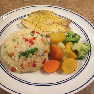 A plate of fish with rice and mixed vegetables.