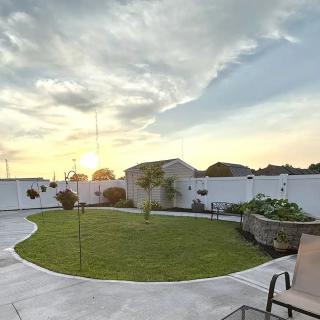 A serene backyard with a grassy lawn and a paved patio, captured at sunset.