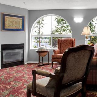 A cozy living room with armchairs, a fireplace, and large windows offering a view of the outdoors.