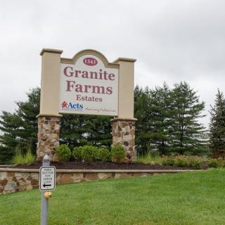 Entrance sign for Granite Farms Estates with surrounding greenery.
