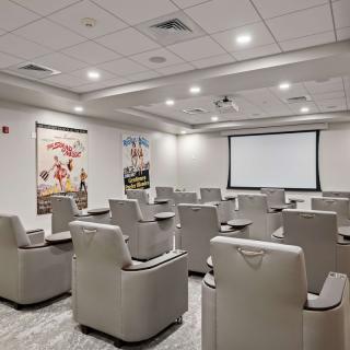 A cozy home theater with comfortable recliner seating and a large screen, flanked by movie-themed posters on the walls.