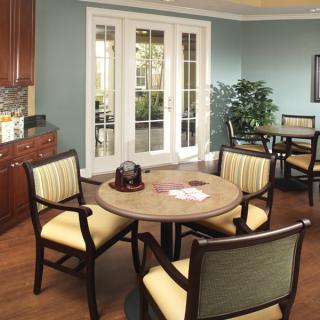 A modern dining room with a round table and upholstered chairs, featuring natural light from glass doors and elegant interior design.