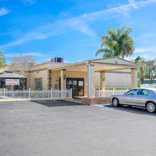 A sunny view of a commercial building surrounded by palm trees and a parking lot.