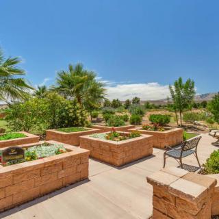 A beautifully landscaped garden with raised brick planters, a pathway, and benches under a clear blue sky.