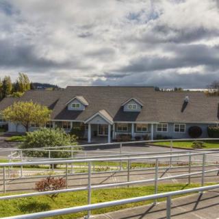 A nursing home building with accessible ramps and surrounding greenery under a cloudy sky.