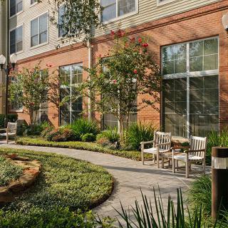 A beautifully landscaped courtyard with outdoor seating and lush greenery alongside a building.