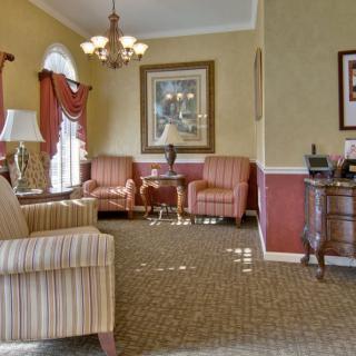A cozy living room with a classic design, featuring striped sofas, an elegant chandelier, and decorative lamps.