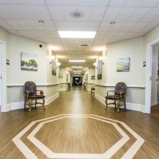 A well-lit hallway with chairs and paintings on the walls.