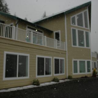 A modern two-story house with large windows and a balcony.