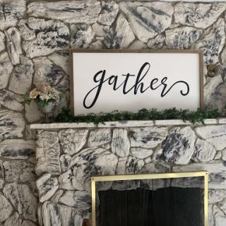 A beautifully decorated fireplace mantel featuring a 'gather' sign, perfect for creating a warm and inviting space.