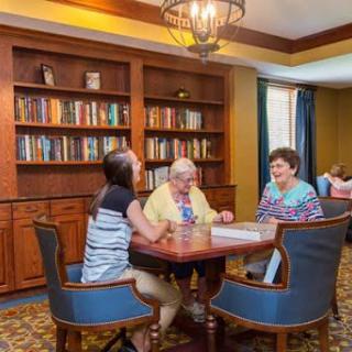 Seniors engaging in a friendly game or discussion in a cozy library setting.